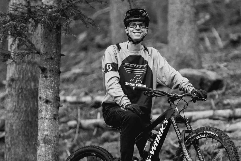 Mountain biker wearing Shore-Carbon gear, smiling while riding on a forest trail